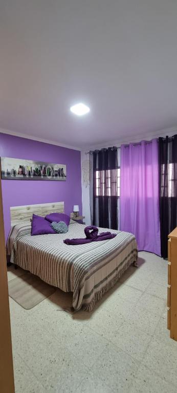 1 dormitorio con paredes moradas y 1 cama grande en vivienda Acerina, en Las Palmas de Gran Canaria