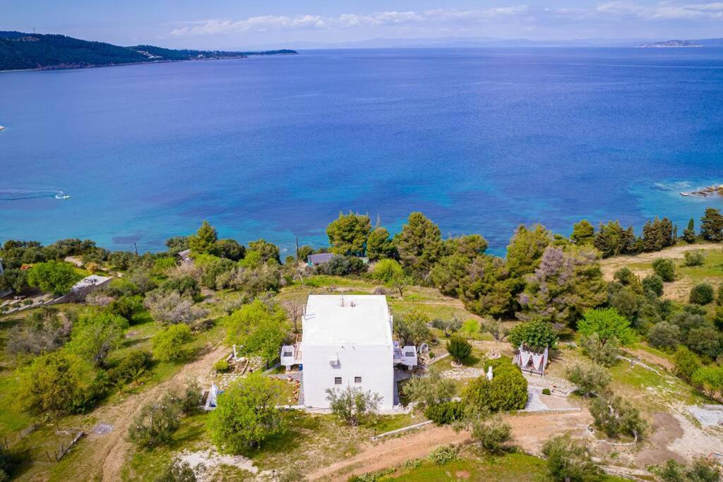 Vue aérienne d'une maison blanche sur une colline à côté de l'eau dans l'établissement Sea Breeze Paradise, à Paliouri