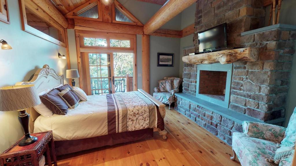 a bedroom with a bed and a stone fireplace at Oneida Lodge North in Cooperstown