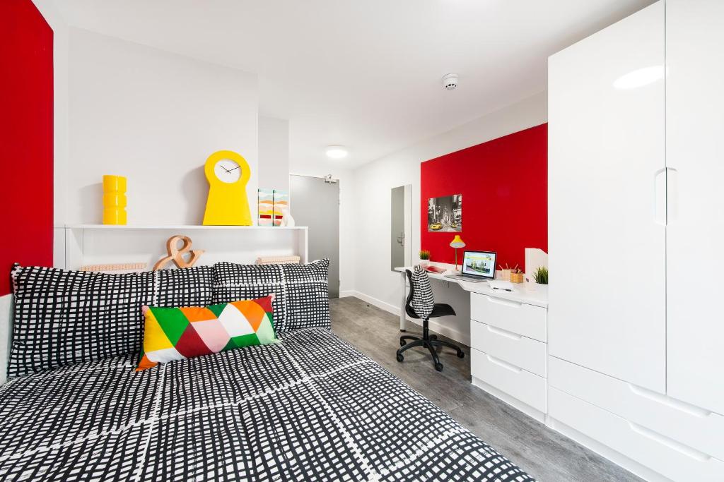 a bedroom with a red accent wall and a bed with a desk at Yugo Explore - Arofan House in Cardiff