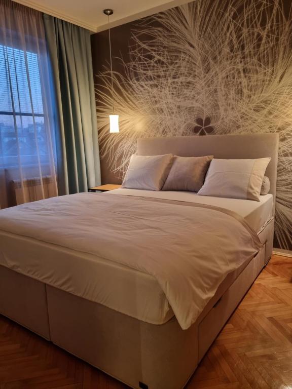 ein Schlafzimmer mit einem großen Bett und einem Fenster in der Unterkunft Apartman Centar in Kraljevo