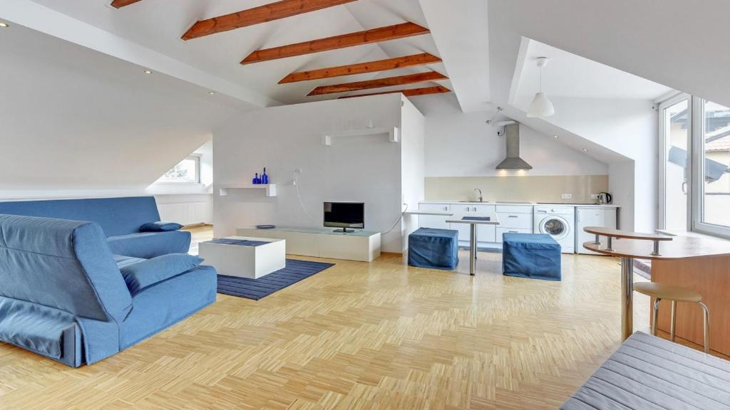 ein Wohnzimmer mit einem blauen Sofa und einer Küche in der Unterkunft Apartamenty Orłowo in Gdynia
