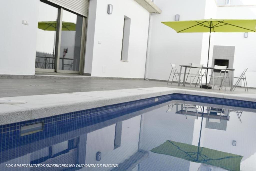 a swimming pool with a table and an umbrella at Apartamentos Turísticos Clavero in Almagro