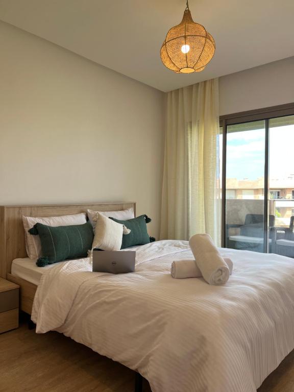 1 dormitorio con 1 cama grande y ordenador portátil en Super appartement familial avec piscine à Prestigia Marrakech en Marrakech