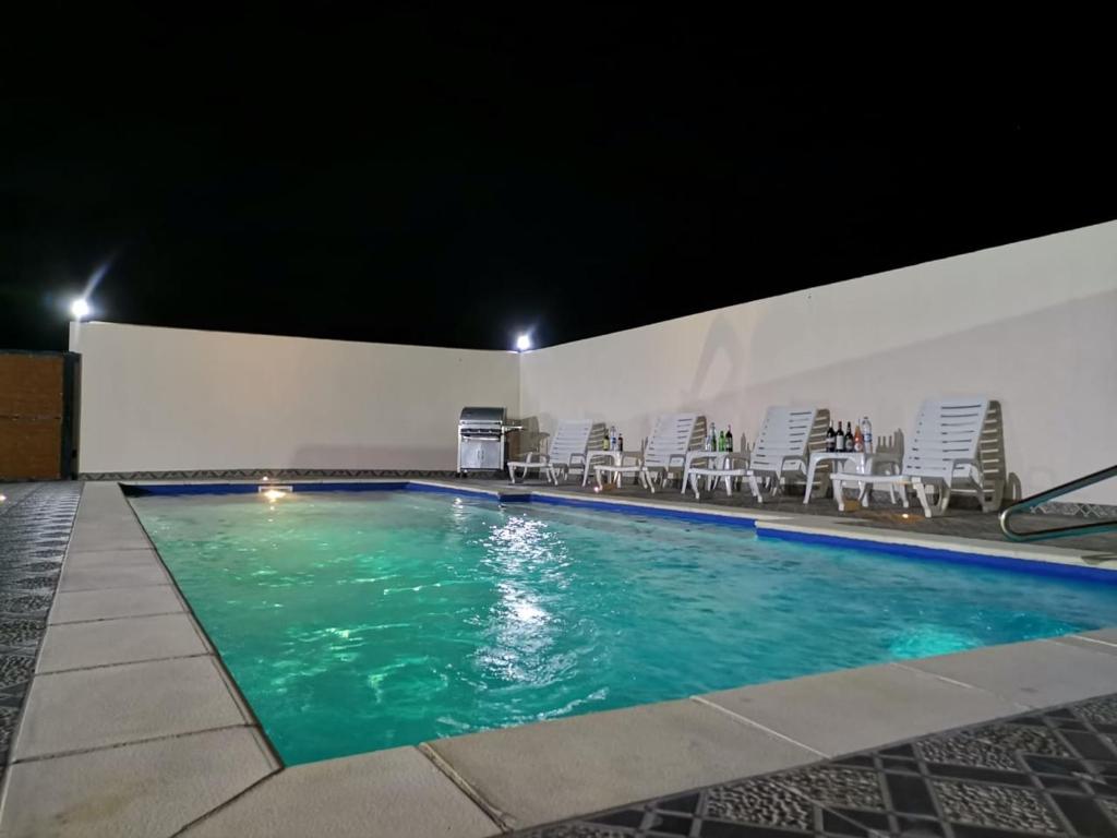a swimming pool at night with chairs and tables at 3A'S COASTAL GUEST HOUSE in Riambel