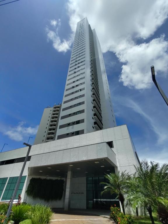 un edificio alto y blanco con palmeras delante en Beach Class Ilha do Leite 2606 en Recife