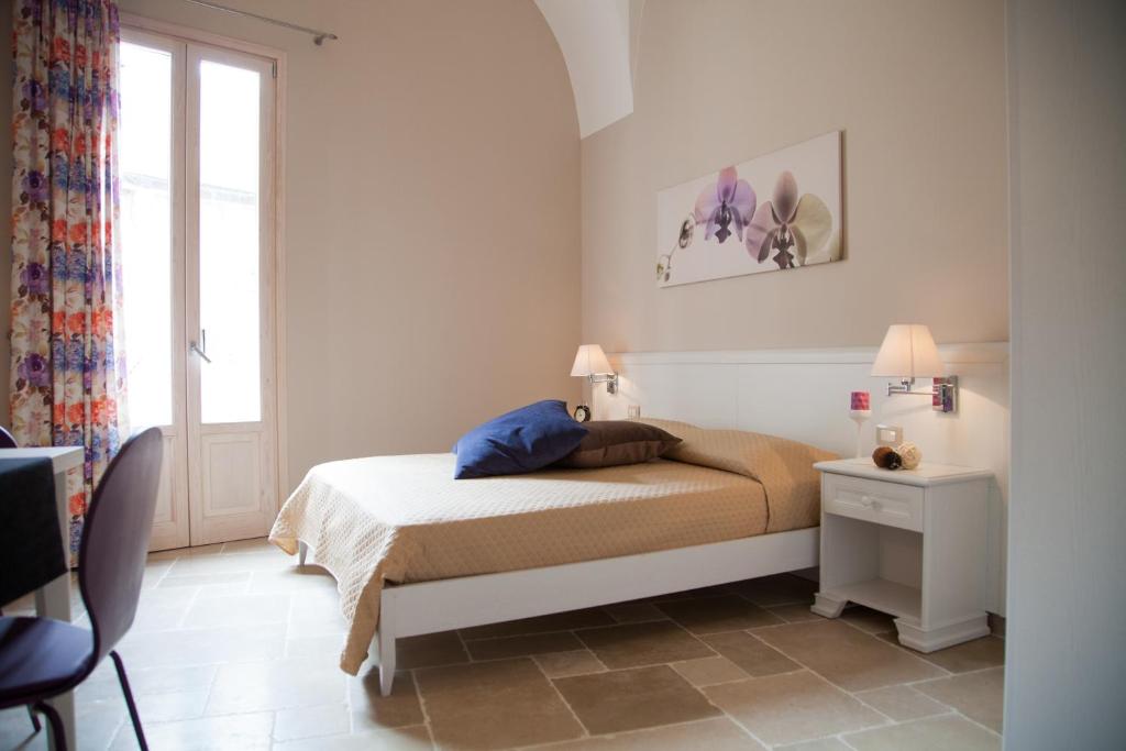 a white bedroom with a bed and a window at Le Stanze di Finya in Gravina in Puglia