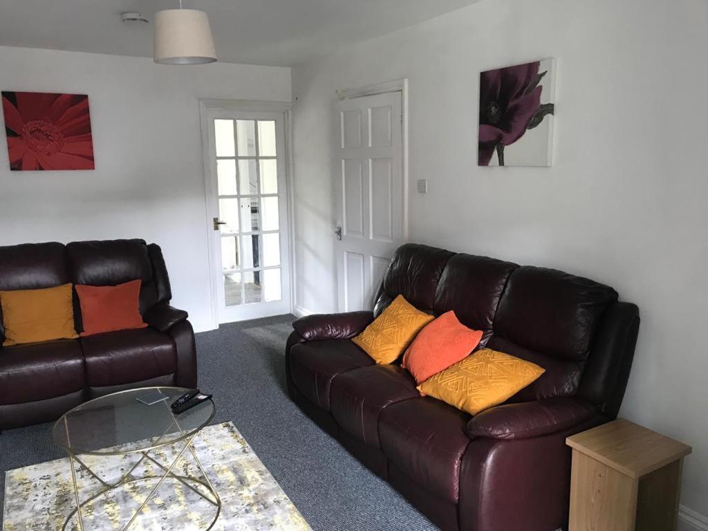 a living room with a leather couch and a table at Accomodation for contractors & professionals 3 bed house with parking in Lighthorne