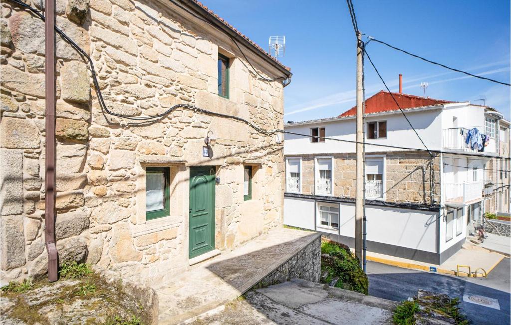 a stone building with a green door on a street at Awesome Home In Muros With Wifi And 2 Bedrooms in Muros