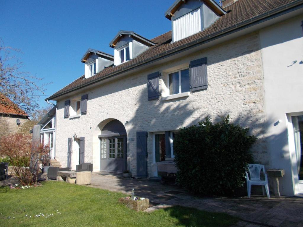 a white brick house with a blue door and windows at Les Petunias in Hugier