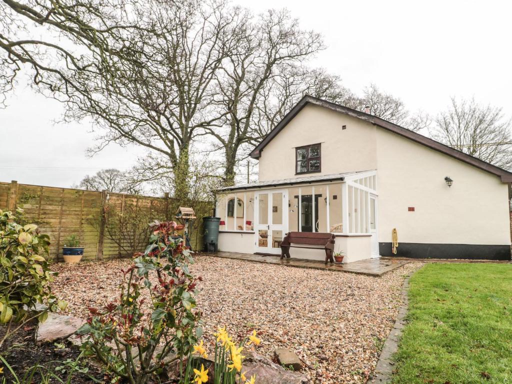 a white house with a bench in a yard at Oak Barn in Cullompton