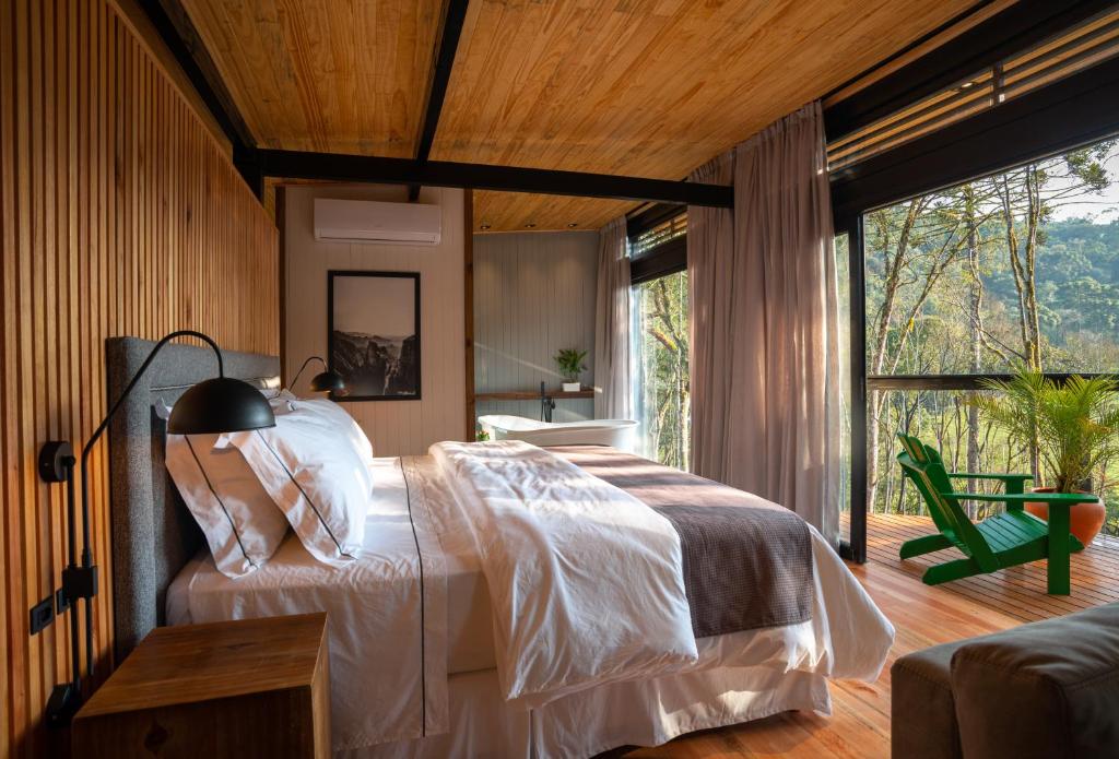 um quarto com uma cama e uma grande janela em Green Barn Hotel & Bistro em Urubici