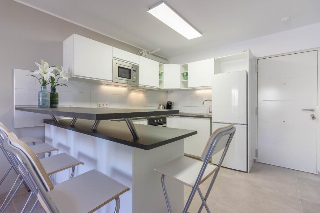 uma cozinha com armários brancos e um balcão com cadeiras em Luxury duplex in Los Cristianos , 6 pax em Los Cristianos