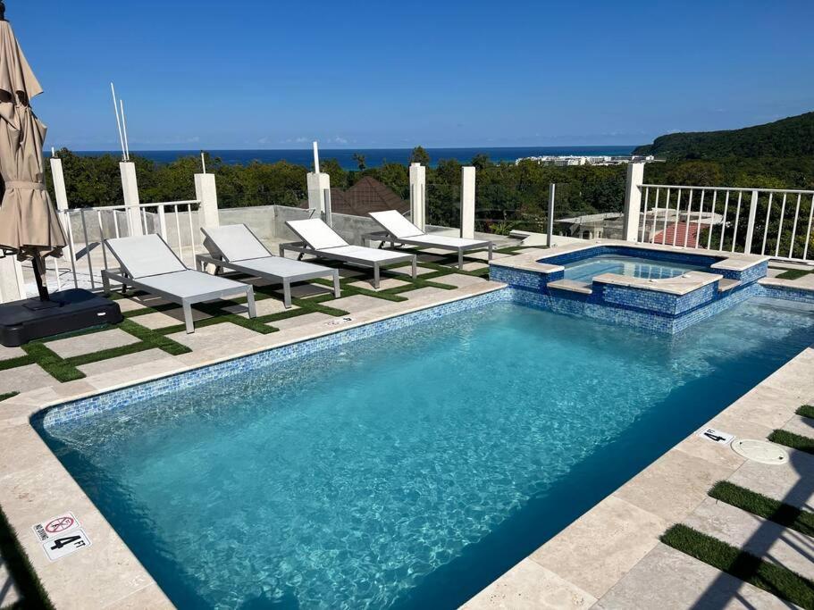 法爾茅斯的住宿－Luxury 1 Bedroom & Rooftop Pool unit #2，游泳池旁带躺椅的游泳池