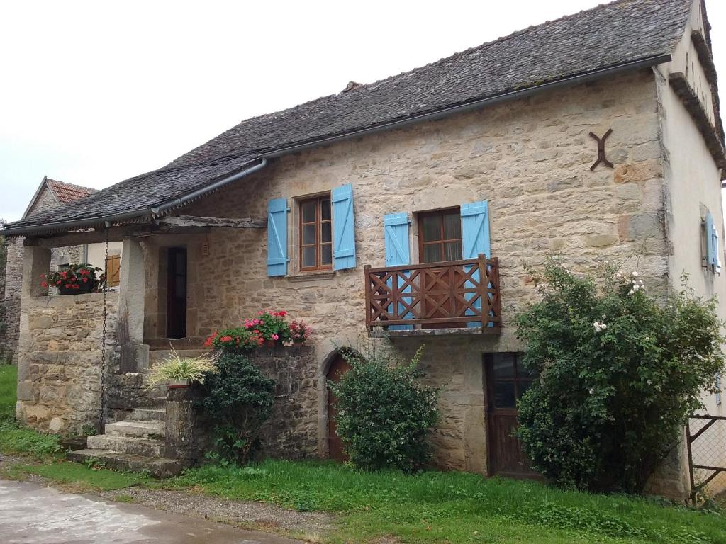 Salvagnac-Cajarc的住宿－Chez carpet，一座古老的石头房子,有蓝色百叶窗和鲜花