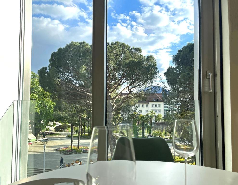 a table with wine glasses in front of a window at Kurhaus Apartment + parking in Merano
