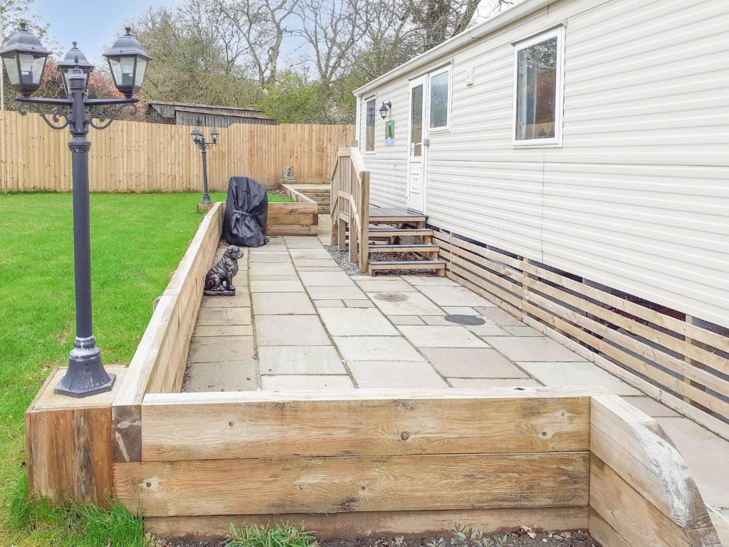 a wooden deck next to a house with a lamp at Doggy Dell in Motcombe