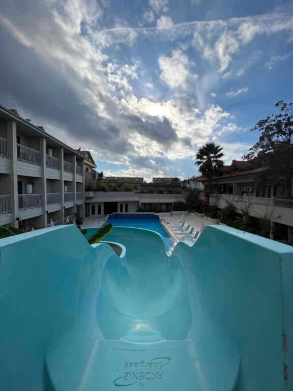 a swimming pool with a blue ramp in front of a resort at İzmah Apart Ölüdeniz in Fethiye