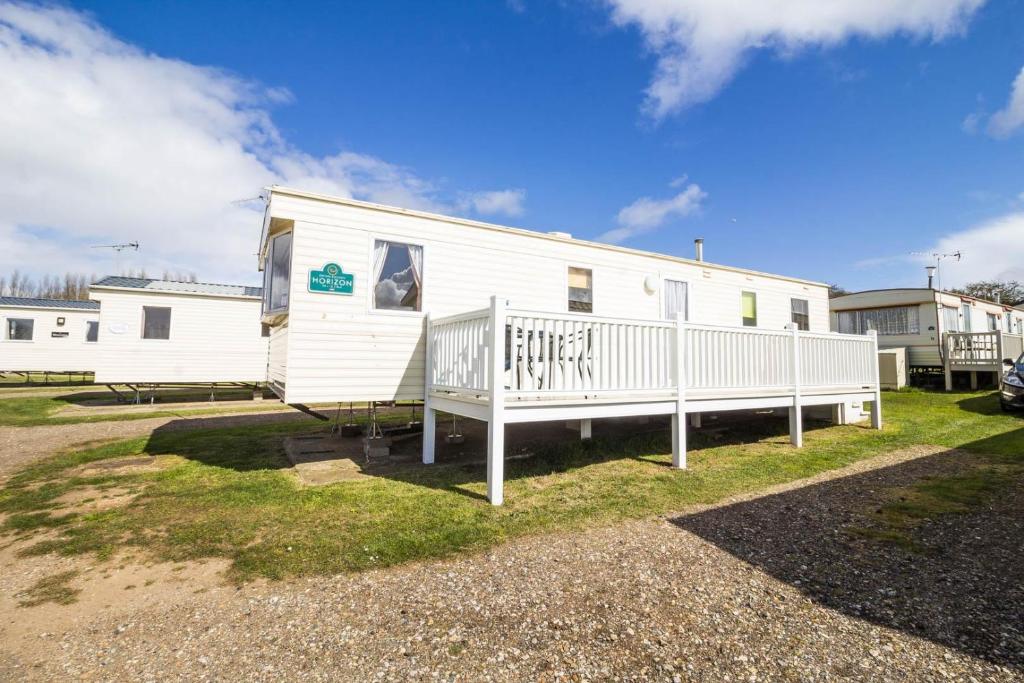a white mobile home with a porch on the grass at 6 Berth Caravan For Hire With Decking At Manor Park In Norfolk Ref 23017s in Hunstanton