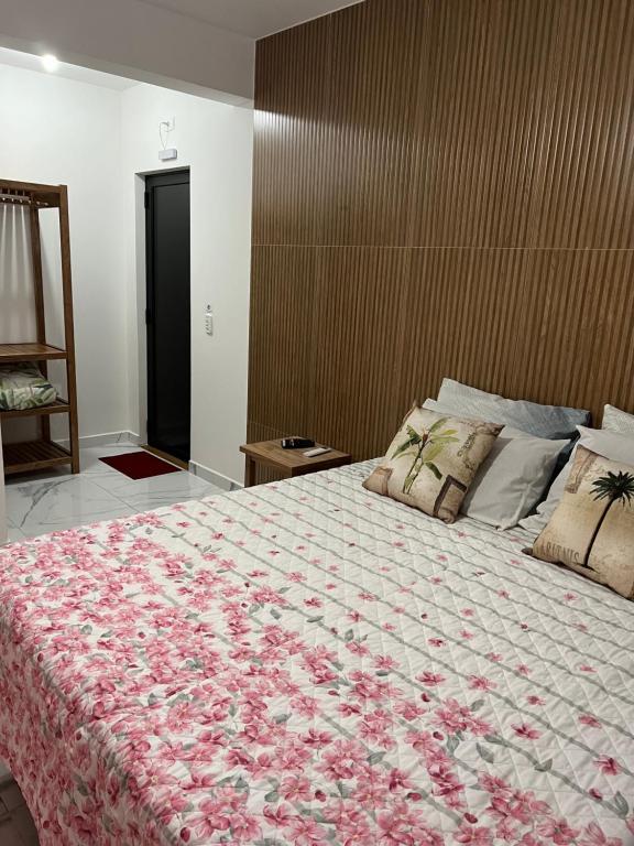 um quarto com uma cama grande e um cobertor floral em Pousada Maria Helena em Guaratuba