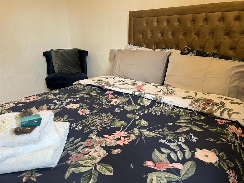 1 dormitorio con 1 cama con colcha de flores en Grand Bleu - London - Next to Piccadilly Line Tube Station & Brand New Facilities, en Londres