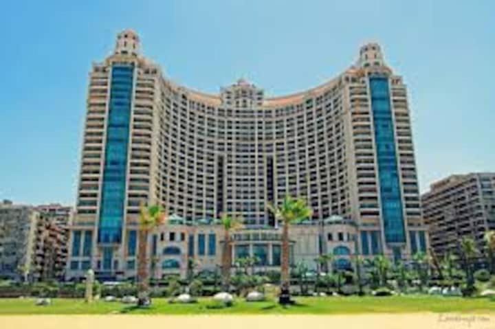 a large building with palm trees in front of it at San Stefano Grand Plaza in Alexandria