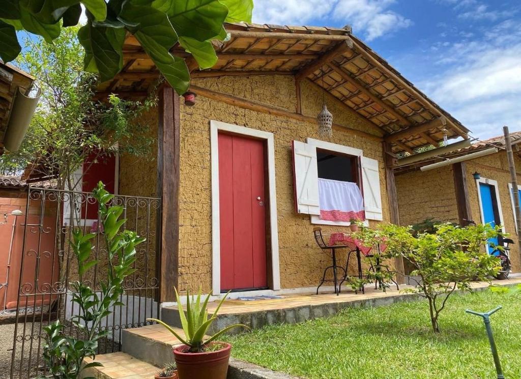 ein kleines Haus mit einer roten Tür und einem Balkon in der Unterkunft Quinta dos Samaniego - Chalés Rústicos in Itaúnas