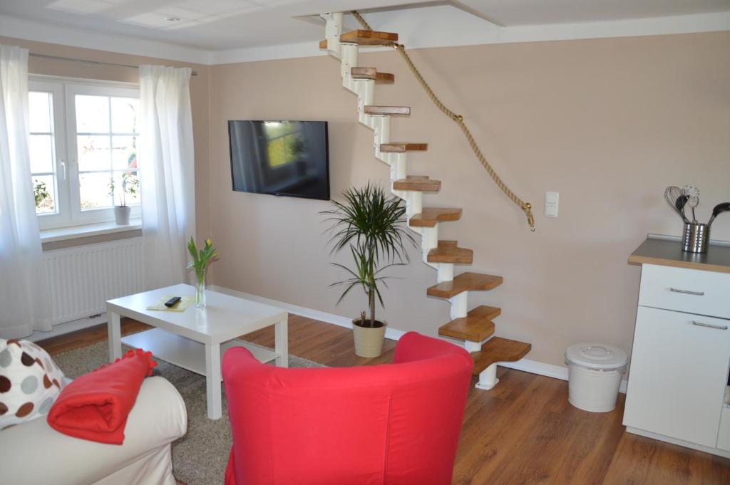 a living room with a red chair and a spiral staircase at Ferienwohnung Gänsemarkt in Born