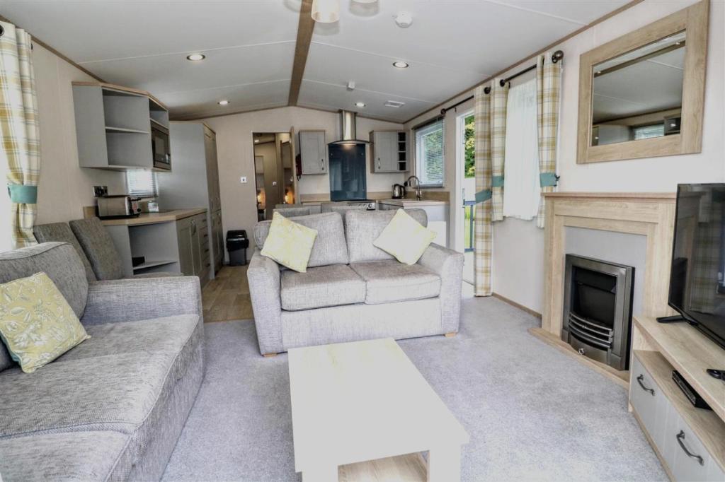 ein Wohnzimmer mit einem Sofa und einem Kamin in der Unterkunft Sunnyside - Willow View in South Cerney