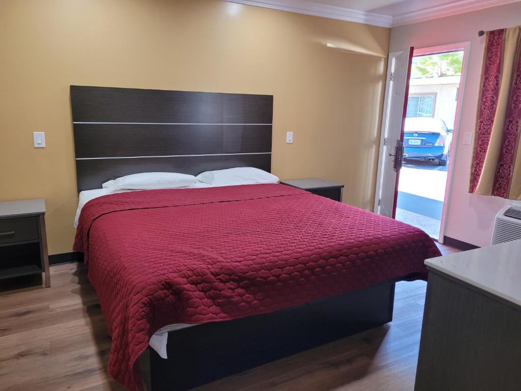 1 dormitorio con 1 cama grande con colcha roja en ACE Motel, en Pasadena