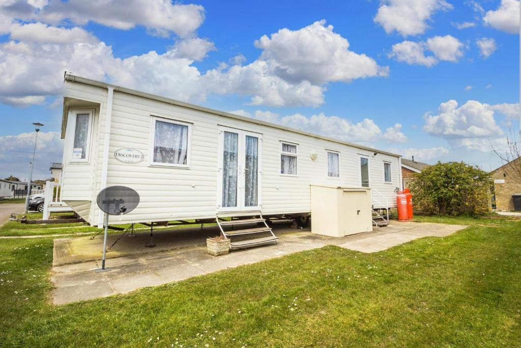 a white mobile home with a grill in a yard at 8 Berth Caravan For Hire At California Cliffs Holiday Park In Norfolk Ref 50046l in Great Yarmouth