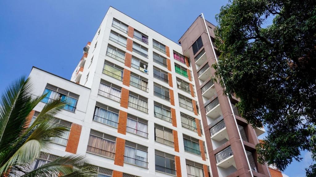 un alto edificio bianco con finestre colorate e una palma di Caliview Apartahotel Andalaya a Cali
