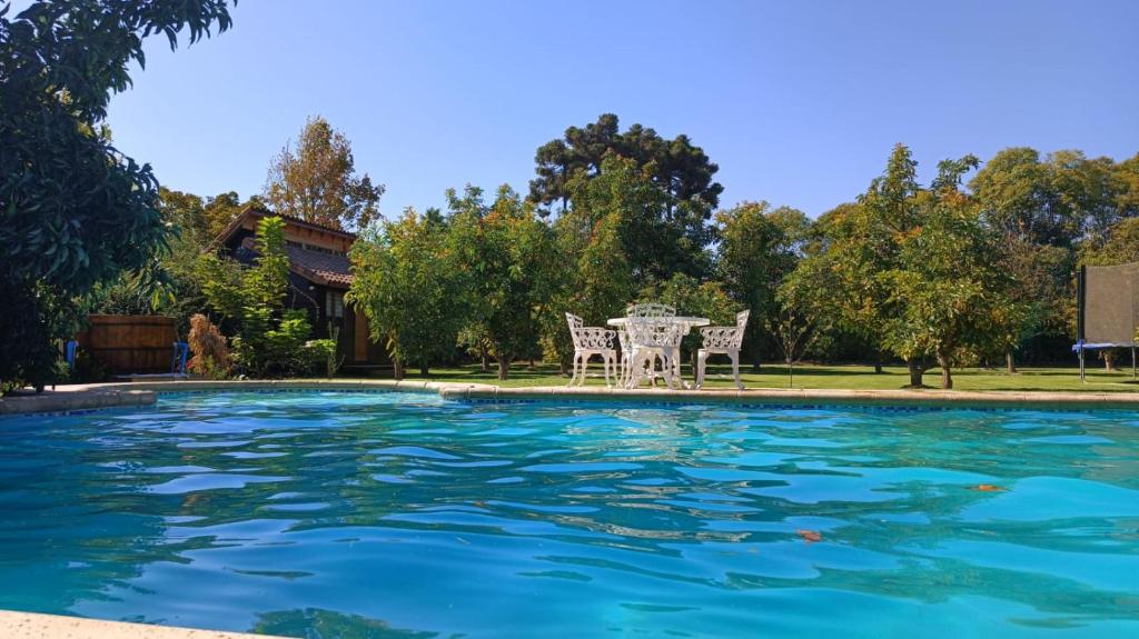 een zwembad met een tafel en stoelen in een tuin bij Loft Cabaña El Recuerdo in Maipo