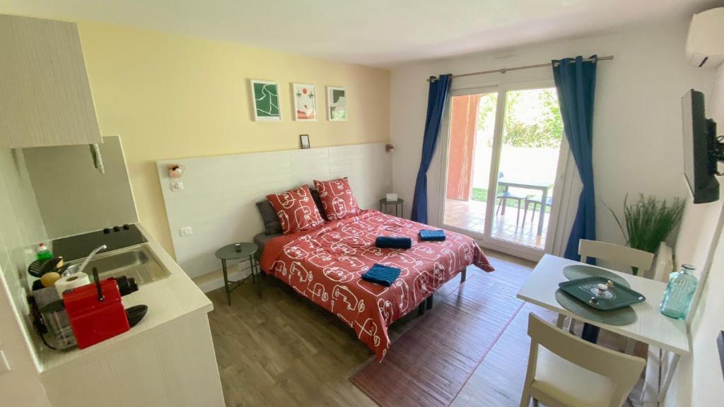 mały pokój z łóżkiem i stołem oraz kuchnią w obiekcie Joli studio Camargue Lou Rouge Arles w mieście Arles