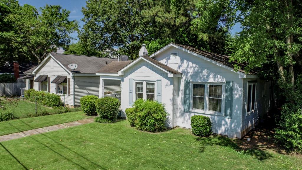 una casa blanca con un patio verde en Bama Bungalow, en Tuscaloosa