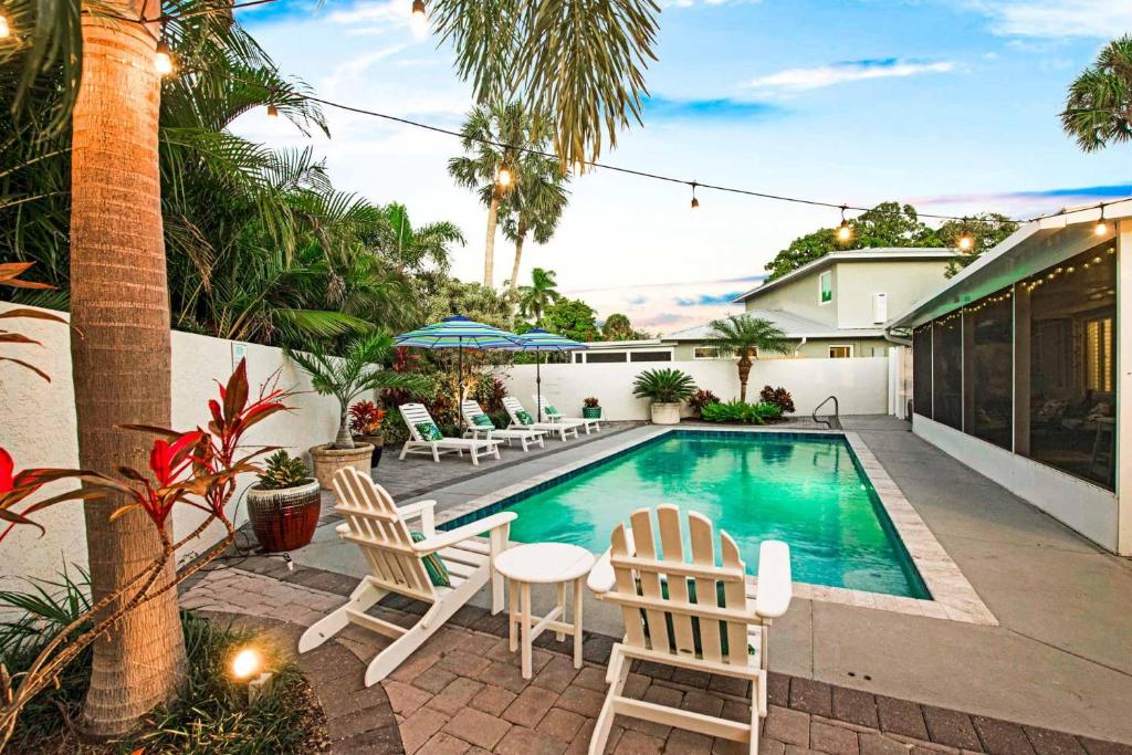 a swimming pool with chairs and a table next to a house at Blue Palm in Bailey Hall