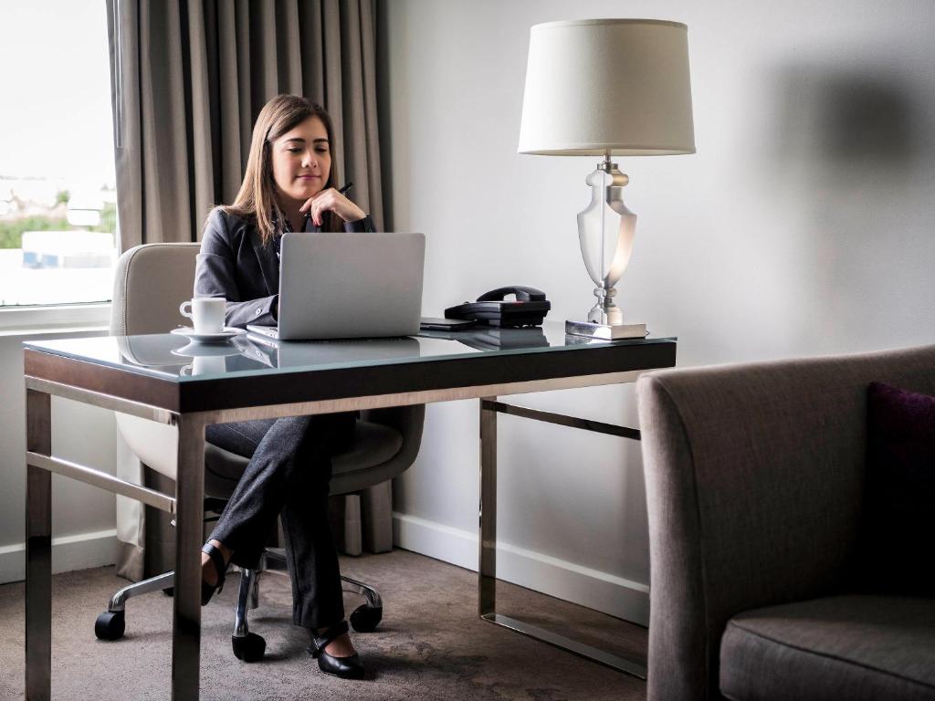 a woman sitting at a desk with a laptop at Pullman Miami Airport in Miami