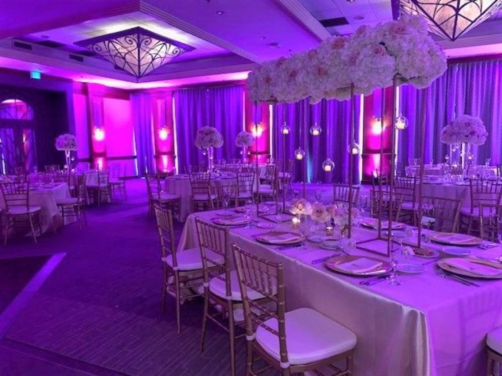 a banquet hall with white tables and chairs and purple lighting at Pullman Miami Airport in Miami