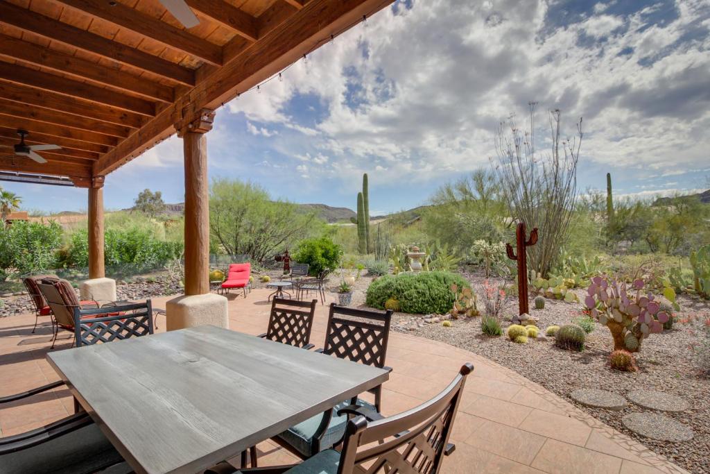 einen Holztisch und Stühle auf einer Terrasse mit Kakteen in der Unterkunft Sunny Tucson Vacation Rental with Patio! in Tucson