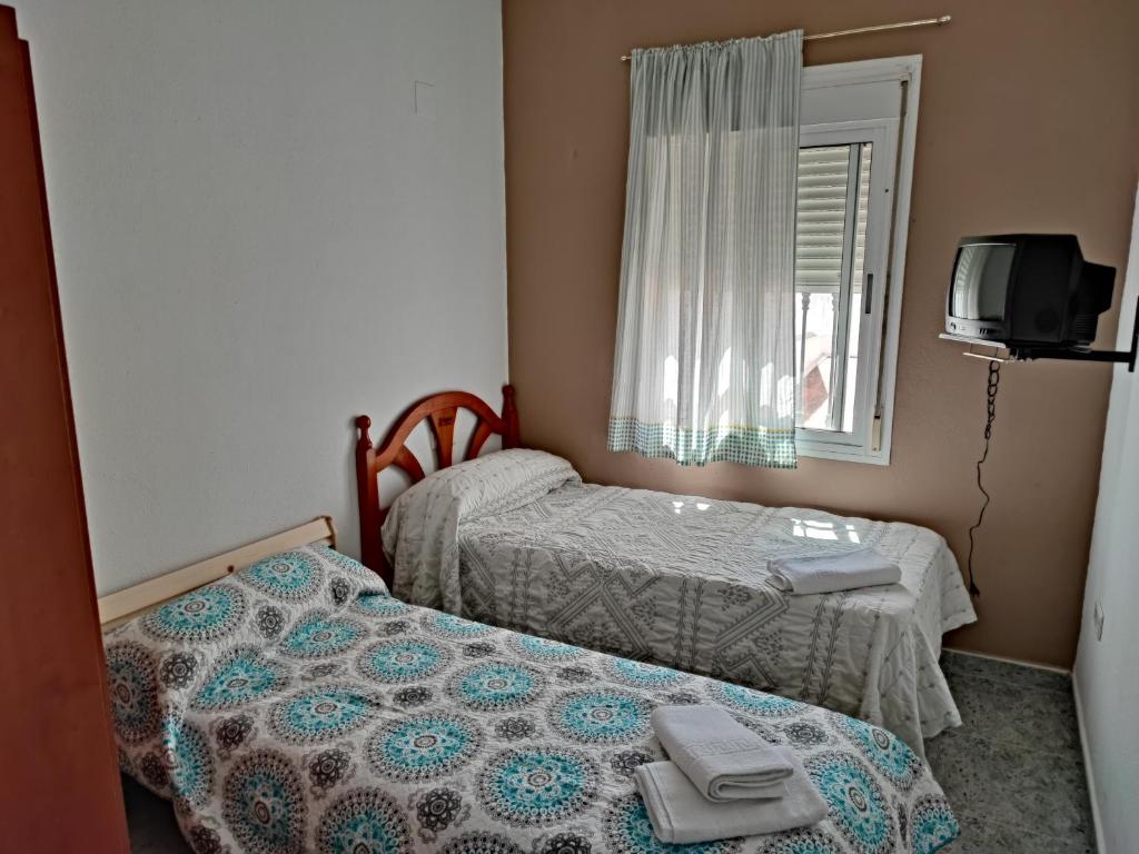 Habitación pequeña con 2 camas y ventana en Centro Isla Cristina en Isla Cristina