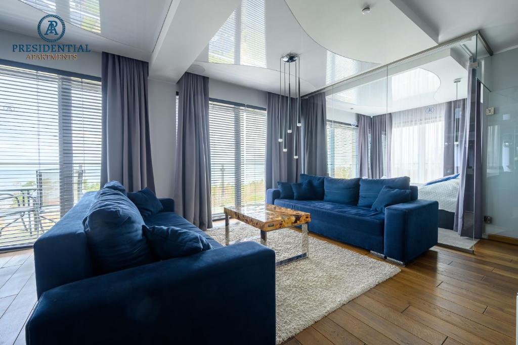a living room with two blue couches and a table at Prezydencki Apartamenty z widokiem na morze in Jarosławiec