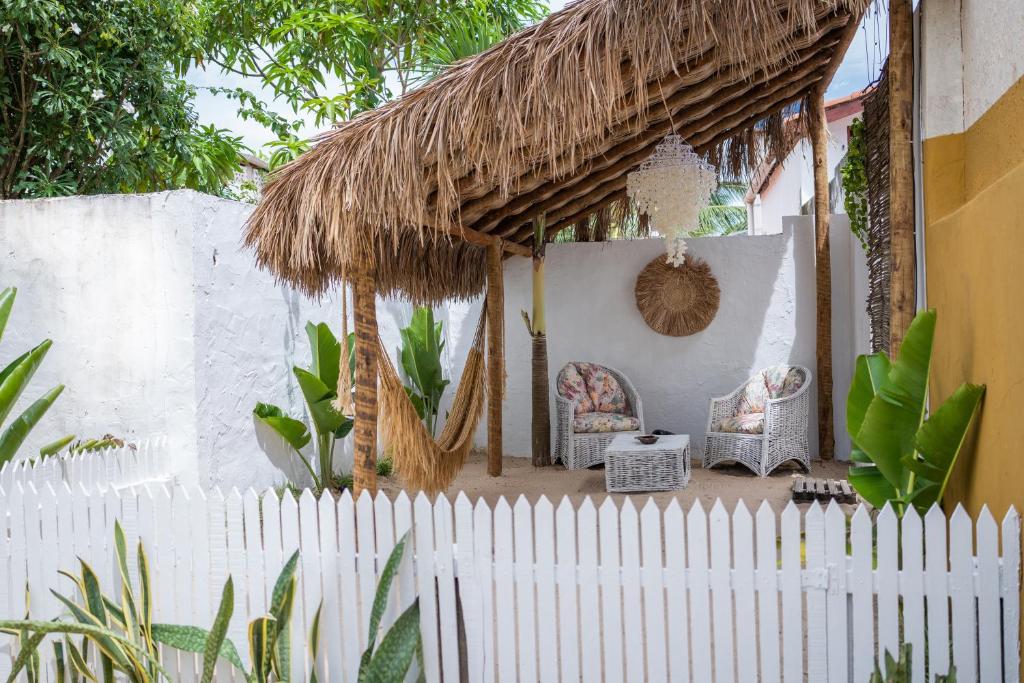 a backyard with a white fence and a thatch roof at casa jasmin in Jericoacoara
