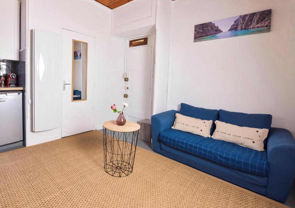 un salon avec un canapé bleu et une table dans l'établissement Aux pieds de la Bonne Mère - Centre - Wifi, à Marseille
