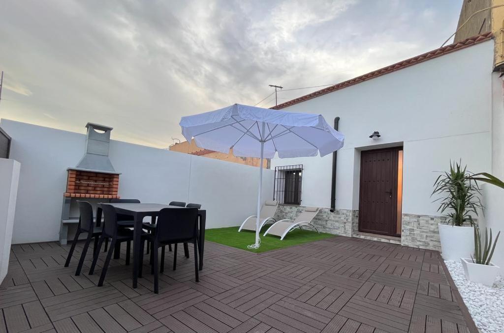 eine Terrasse mit einem Tisch, Stühlen und einem Sonnenschirm in der Unterkunft Casa La Zurita in Tabernas