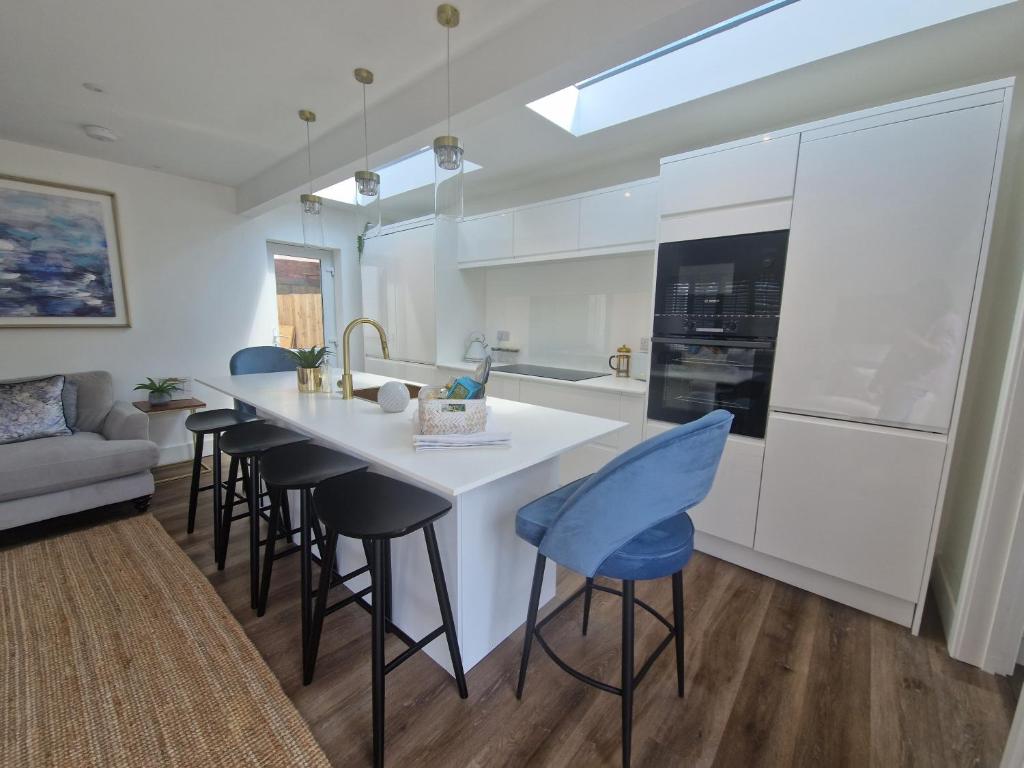 a kitchen with a large white island with stools at Seaside Apartment, Parking, Private Garden, 5 min Stroll from the Beach in Bournemouth