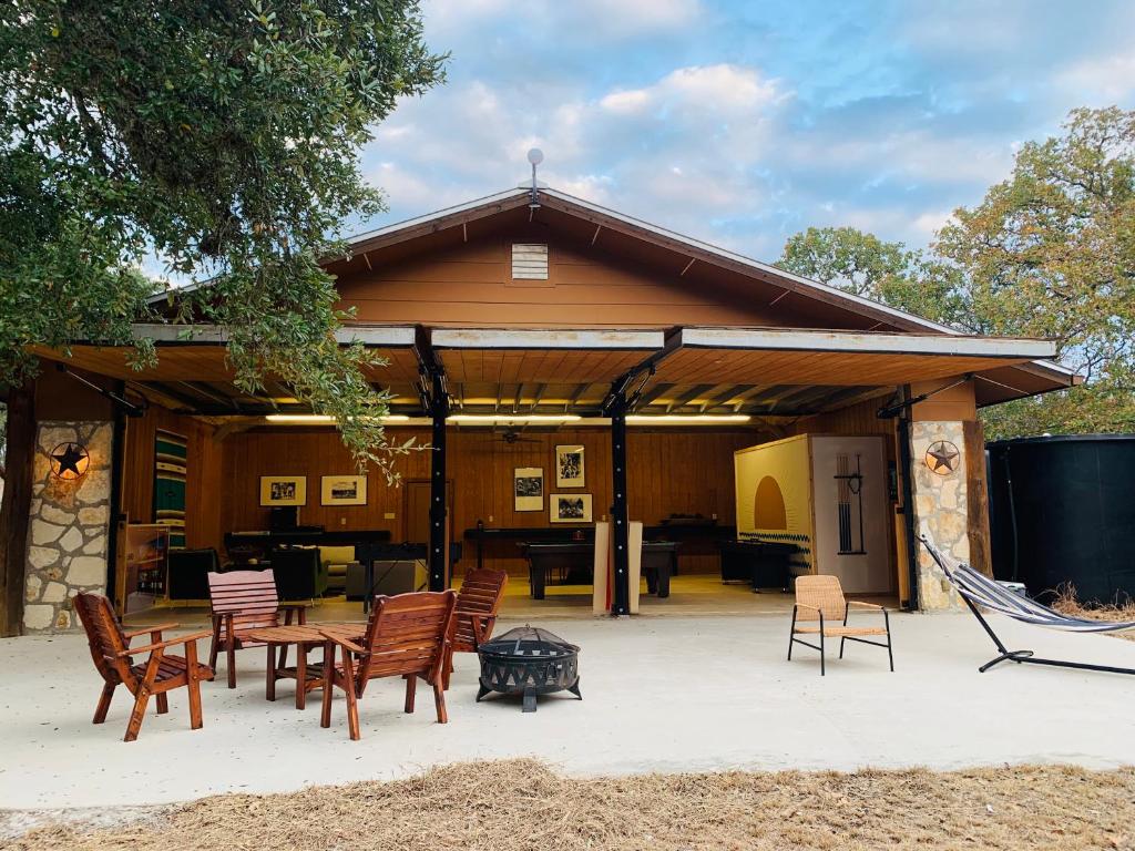 a patio with chairs and a table and a grill at The Camp Blanco by Lodgewell - Riverfront retreat 2 Homes, Bunk House, Game Room & more in Blanco