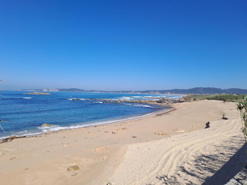 a sandy beach with the ocean in the background at Desconectaengalicia La Lanzada, a pie de playa in A Lanzada