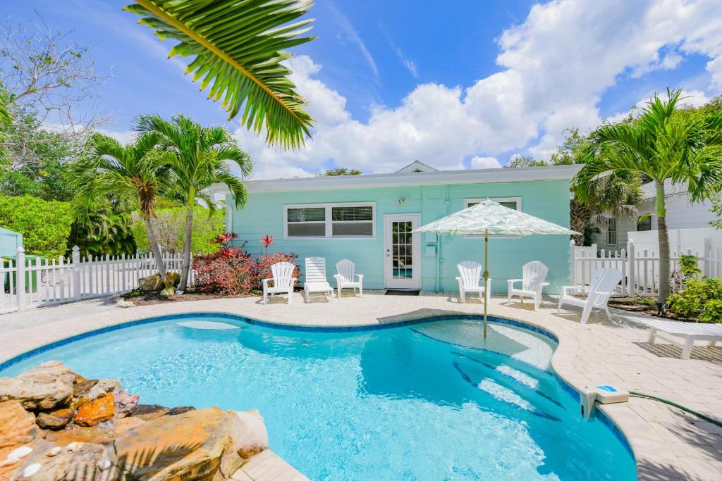 a pool with chairs and an umbrella in front of a house at Beach Side Babe in Sarasota