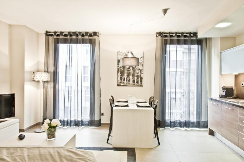 salon ze stołem oraz kuchnia z oknami w obiekcie Up Suites BCN w Barcelonie