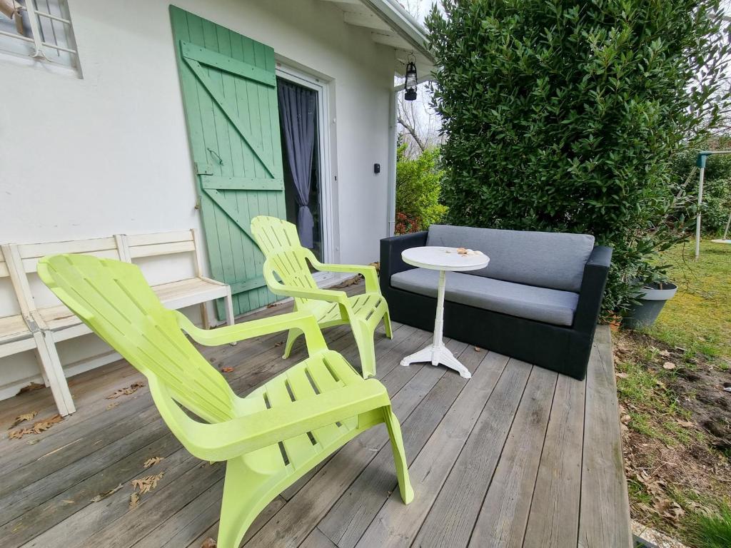 two chairs and a table and a couch on a deck at La Cabane aux Acacias~vacances nature et au calme in Mézos